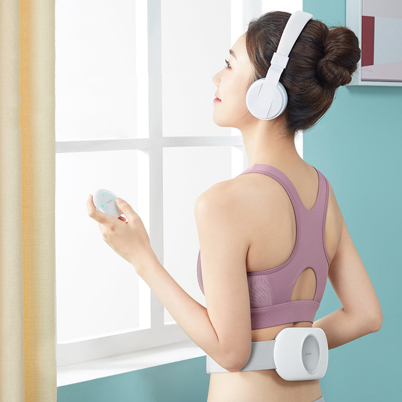 Woman wearing a purple sports bra and white headphones, holding a remote control, in a room with a window.