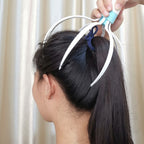 Person using a hair styling tool on their hair with a neutral background